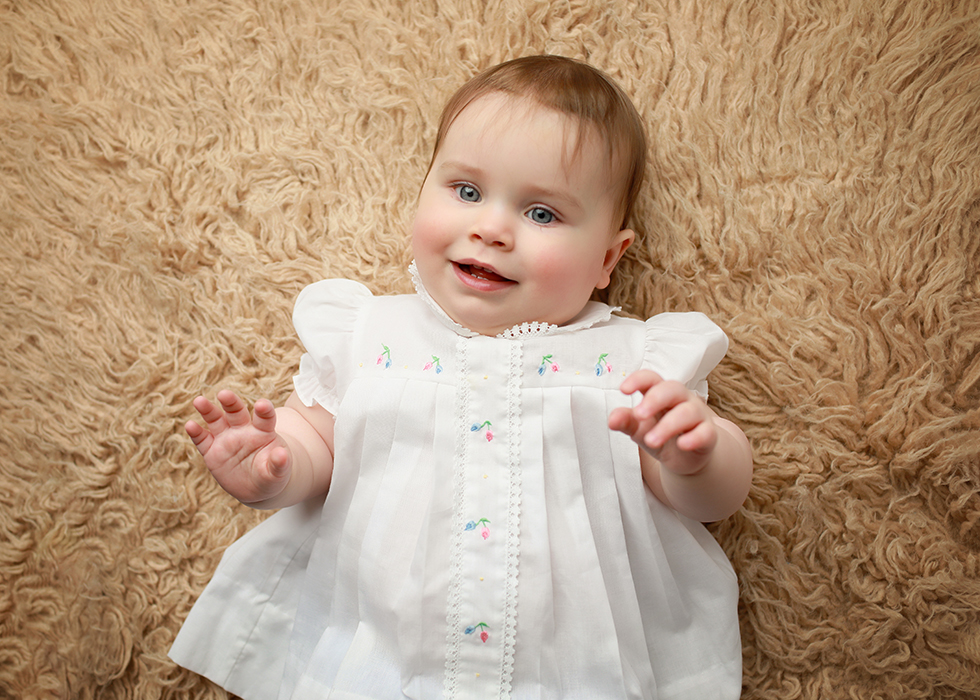 Baby girl in white dress laying down
