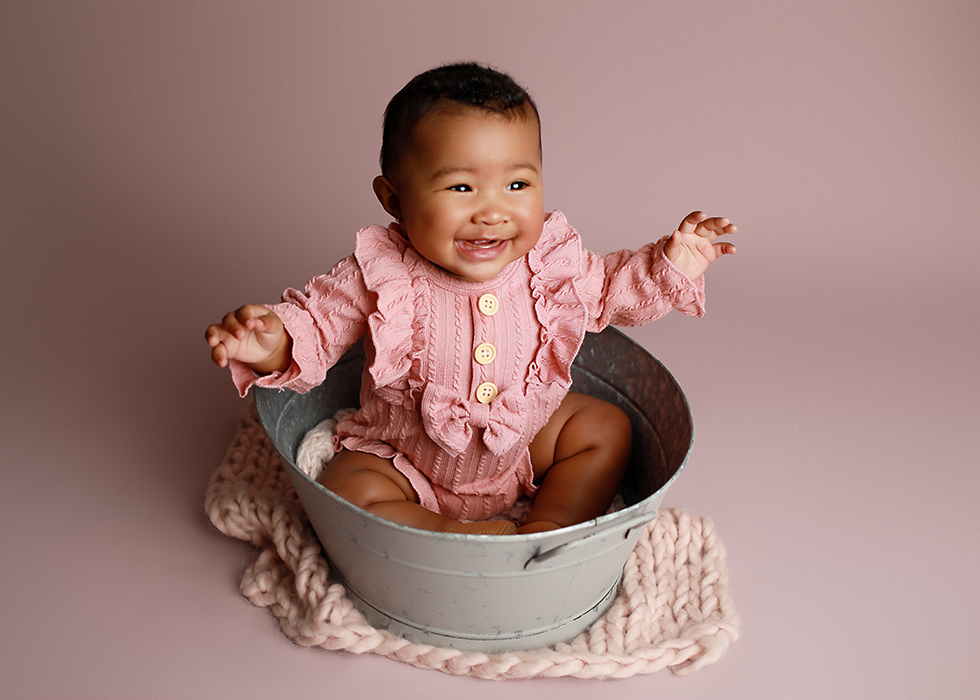 6 Month Old baby girl sitting up in a bucket
