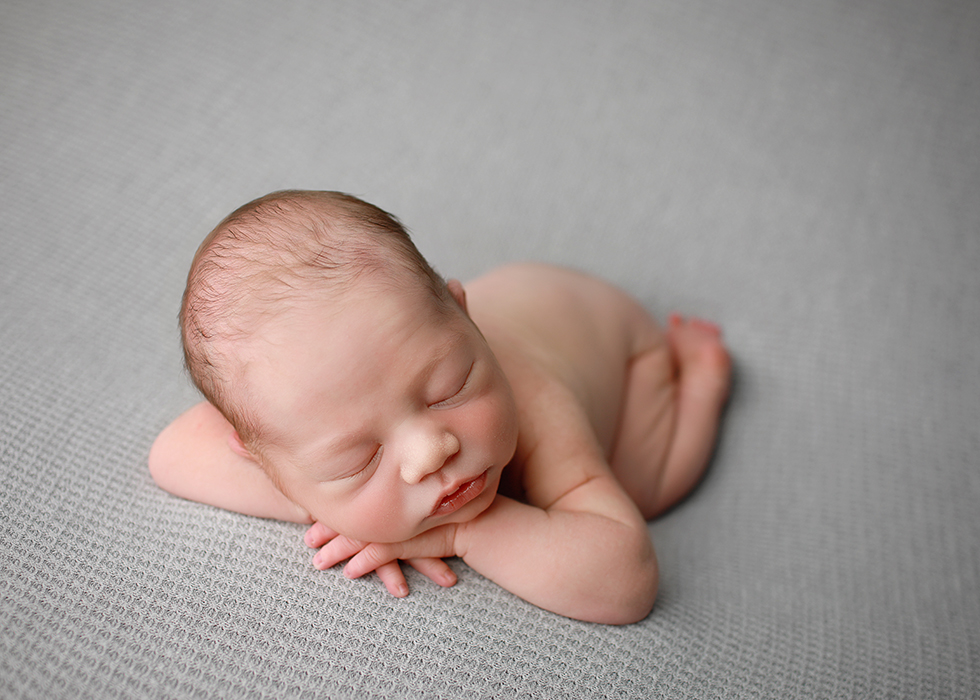 newborn sleeping boy on a grey blanket