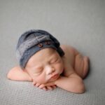 baby boy posed for newborn photoshoot on grey blanket