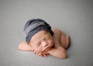 baby boy posed for newborn photoshoot on grey blanket