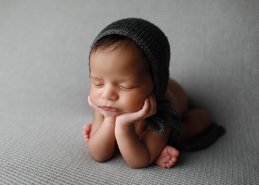 Newborn baby boy posed in gray bonnet by Wake Forest newborn photographer Melissa DeVoe